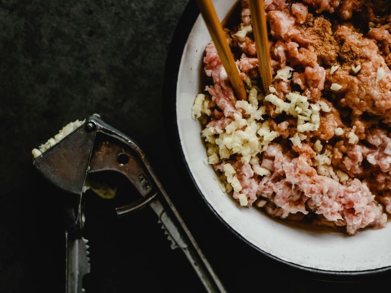 Old garlic press near chopped food bowl