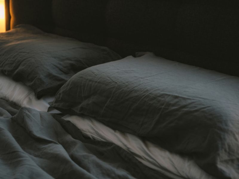 grey bedsheet with grey and white pillow on bed
